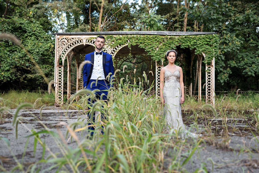A bride and groom pose for a portrait in the middle of ruins of an old tennis court at Alverthorpe Manor in Bucks County.